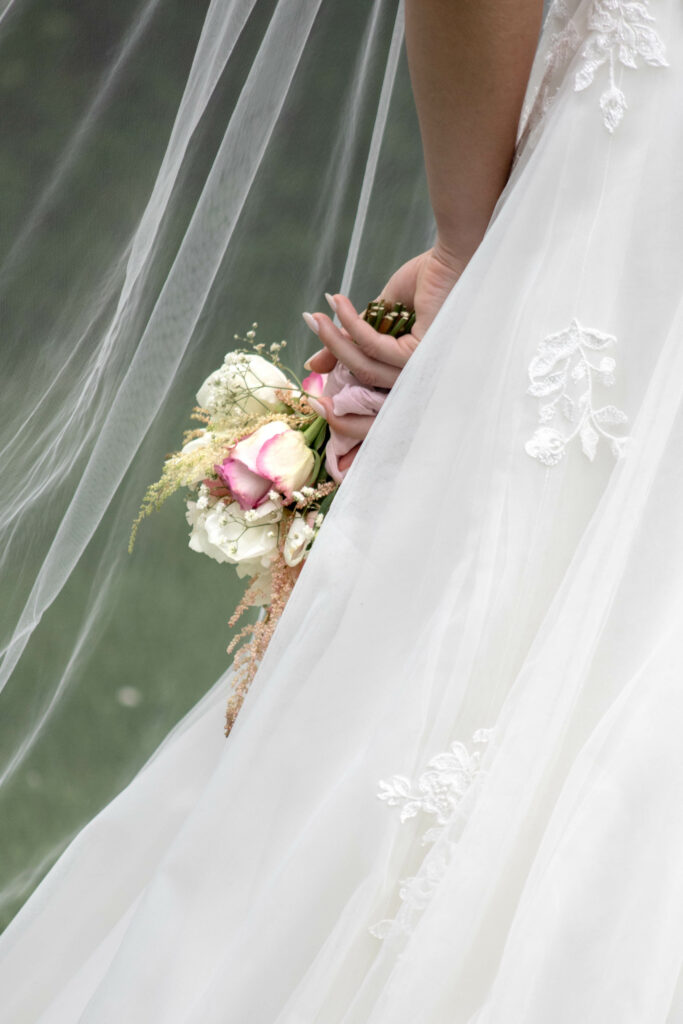 Mariée qui tient son bouquet rose près de son voile