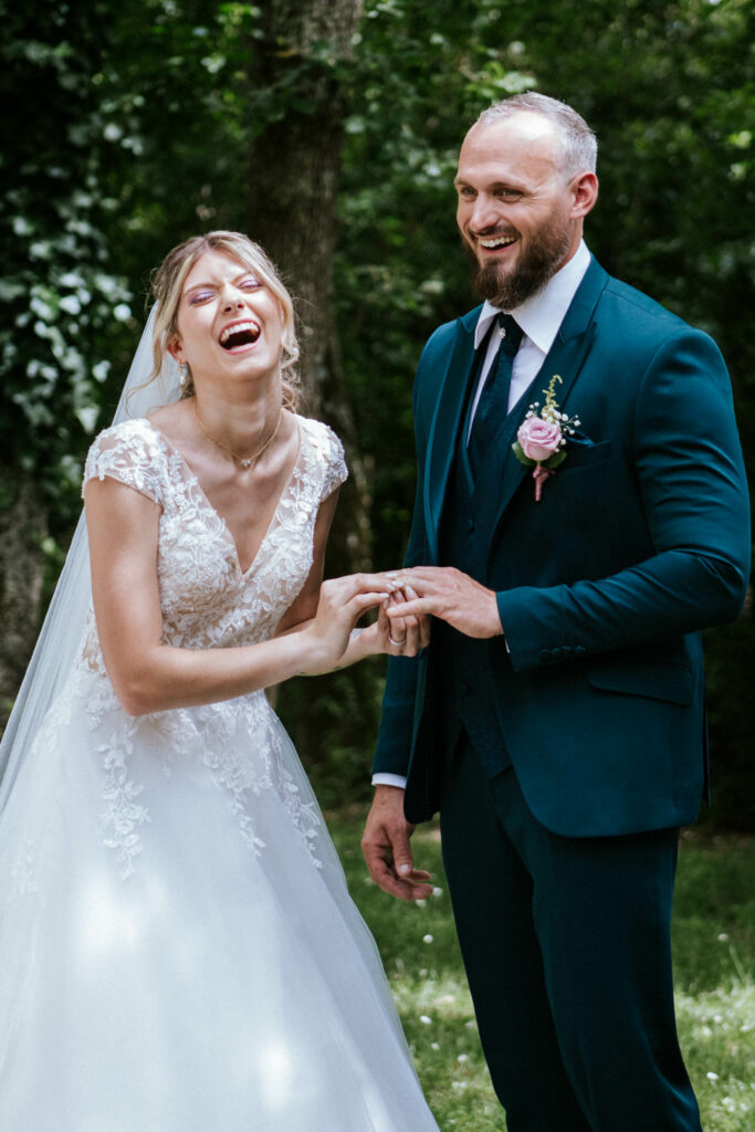 mariée qui rie au moment de passer l'alliance à son mari