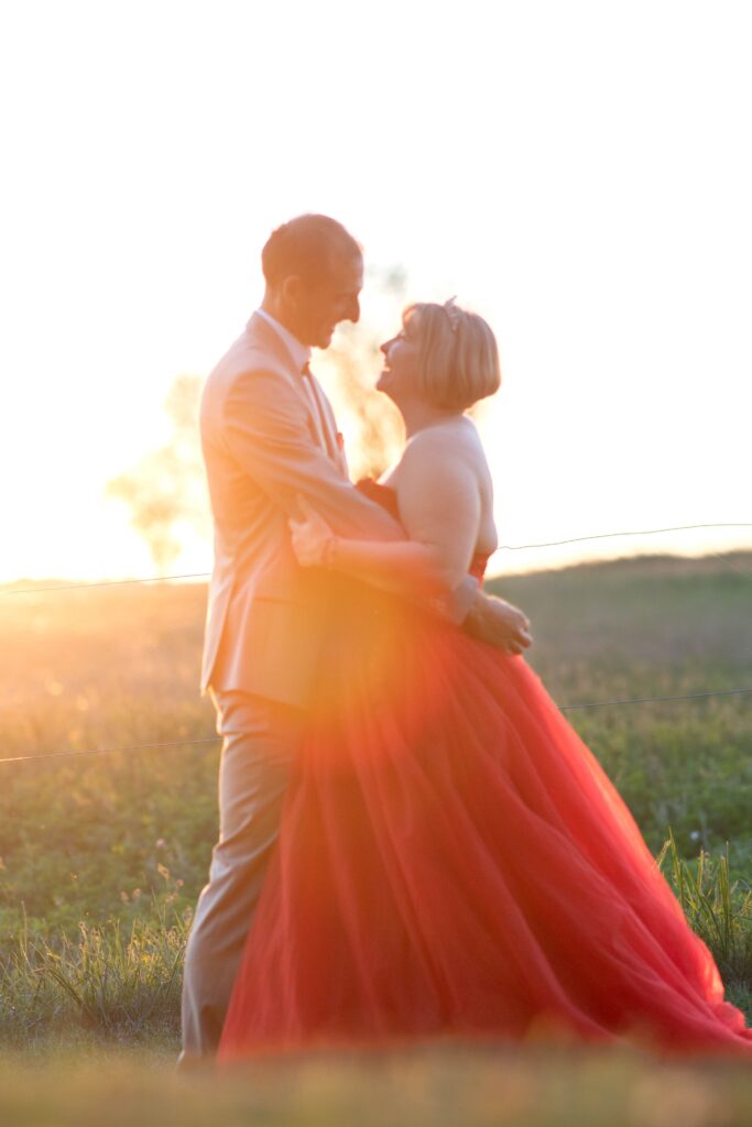 Le marié regarde avec bonheur sa mariée lors d’une douce soirée en plein air.