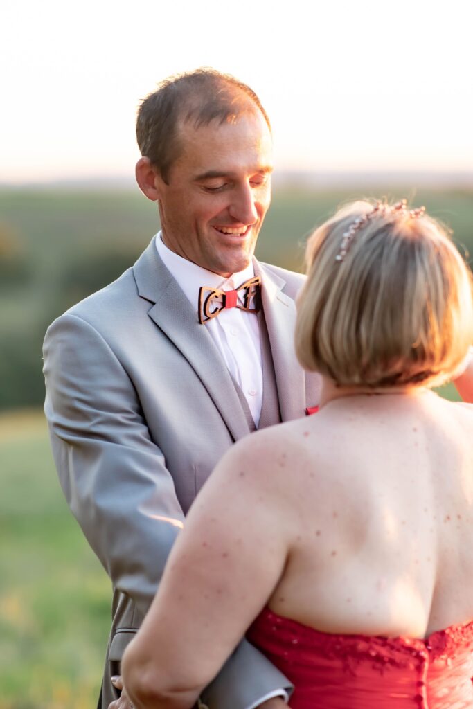 Marié radieux, souriant à sa mariée lors d’un moment romantique capturé en plein air.