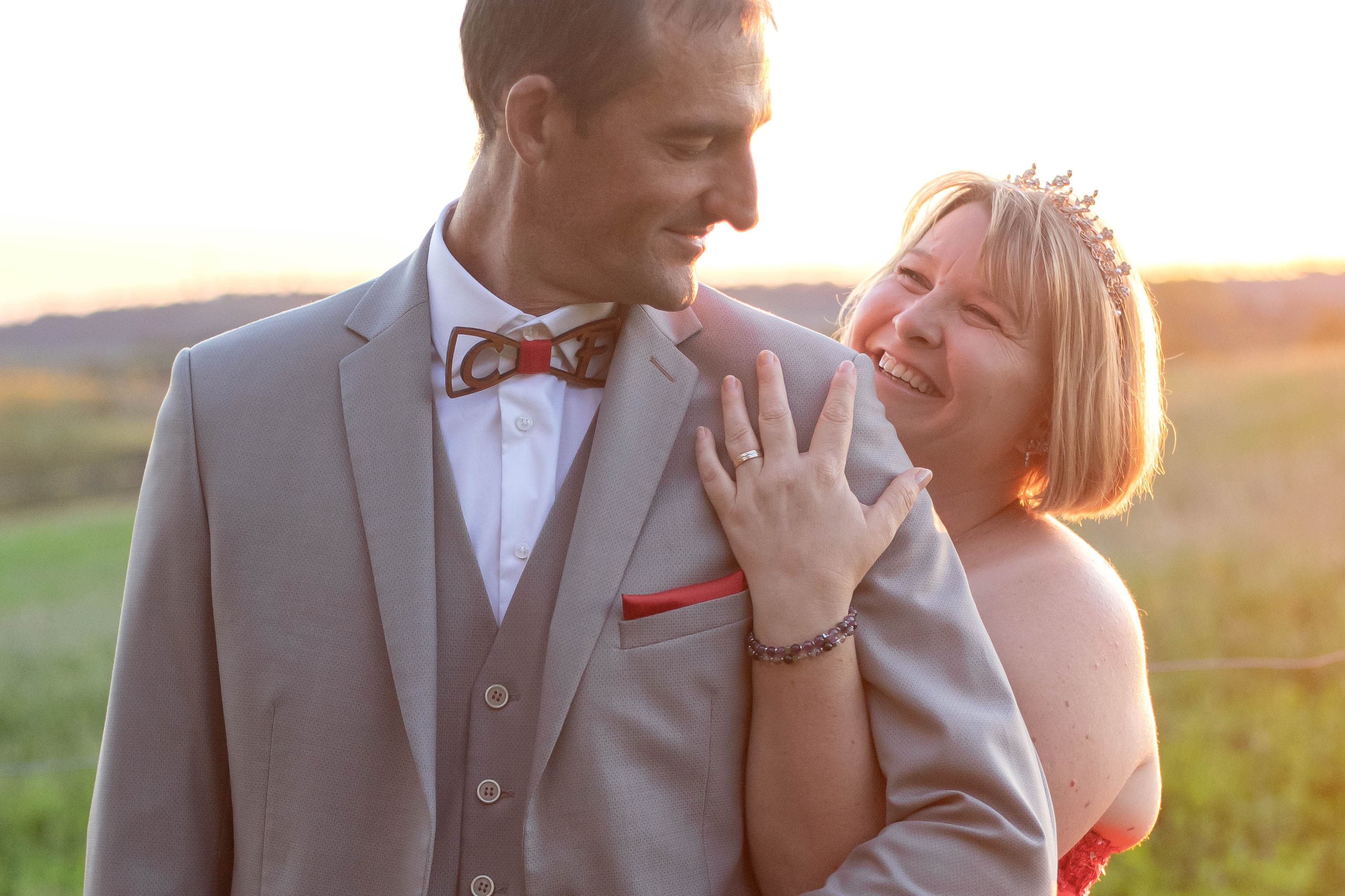 Les alliances des mariés brillent sous la lumière naturelle, la mariée habillée d’une élégante robe rouge