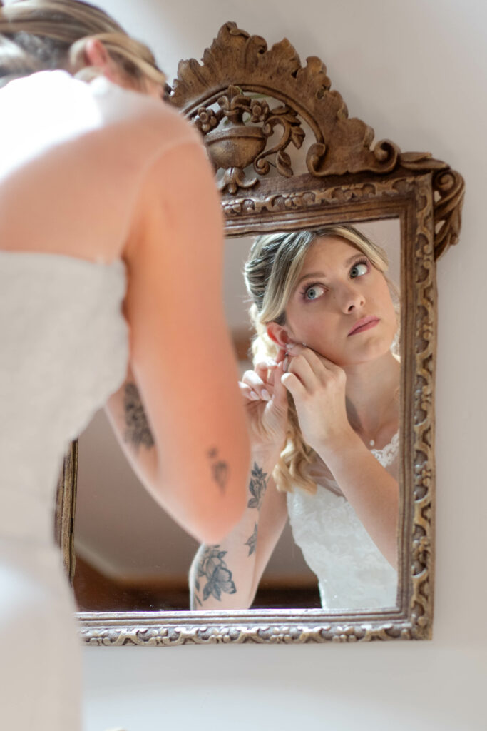 la mariée qui se remet ses bijoux face à un beau miroir ancien doré