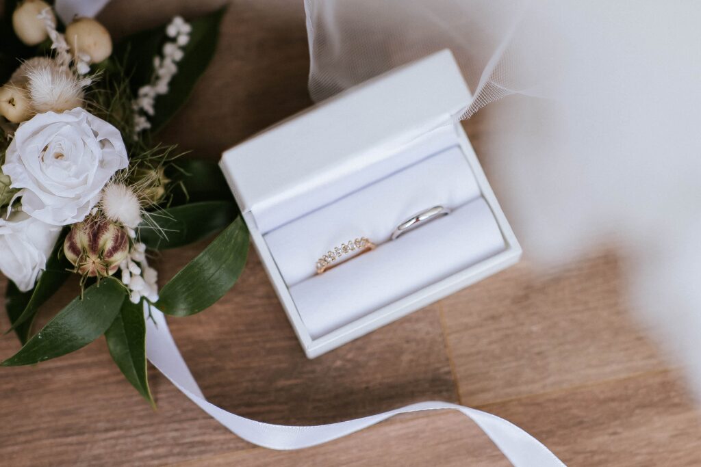 Alliance de mariage et bague de fiançailles dans un écrin blanc, accompagnées d'un bouquet de mariée à Castres